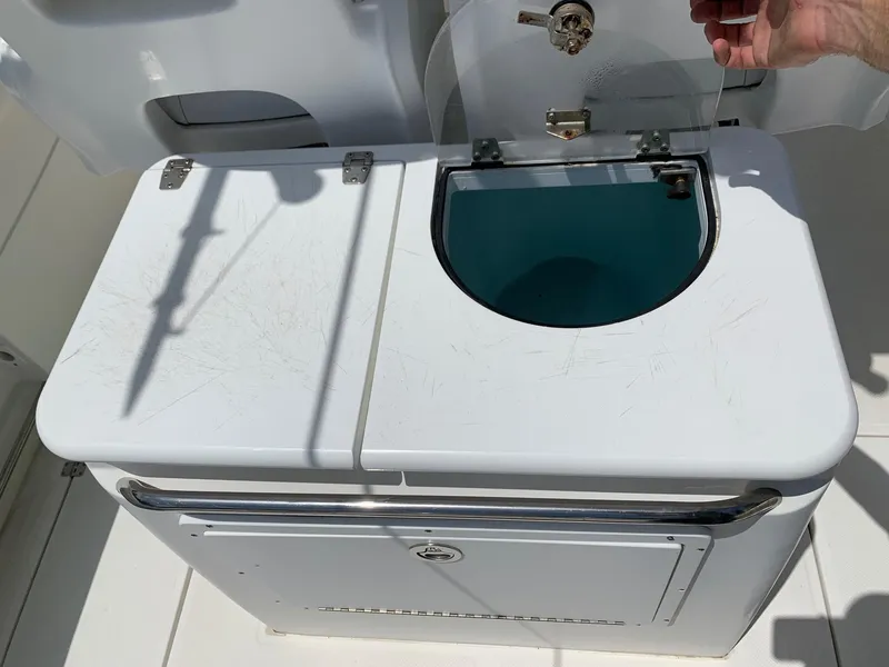 Slide: The Image of 2013 Sea Fox 286 CC livewell with open lid and hand holding latch. - 11