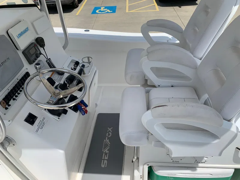 Slide: The Image of 2013 Sea Fox 286 CC boat cockpit with dual white captain chairs and steering console. - 13