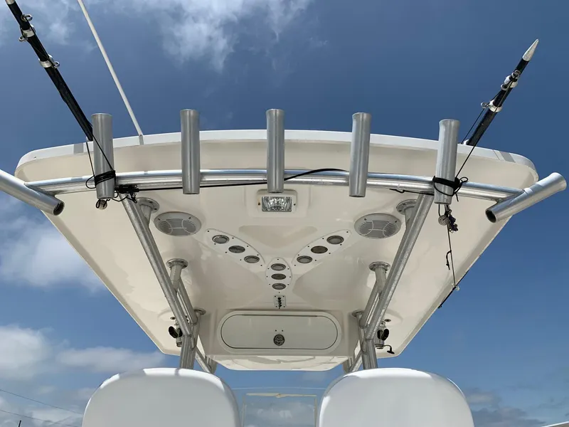 Slide: The Image of 2013 Sea Fox 286 CC boat T-top with rod holders and speakers against blue sky. - 4