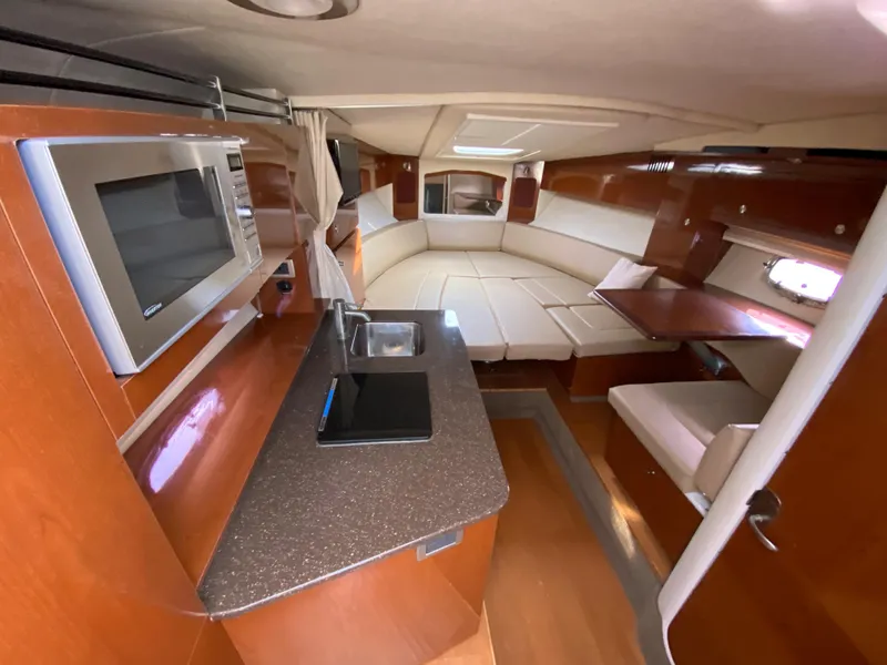Slide: The Image of Interior of 2013 Sea Ray 310 Sundancer yacht with kitchenette and seating area. - 11