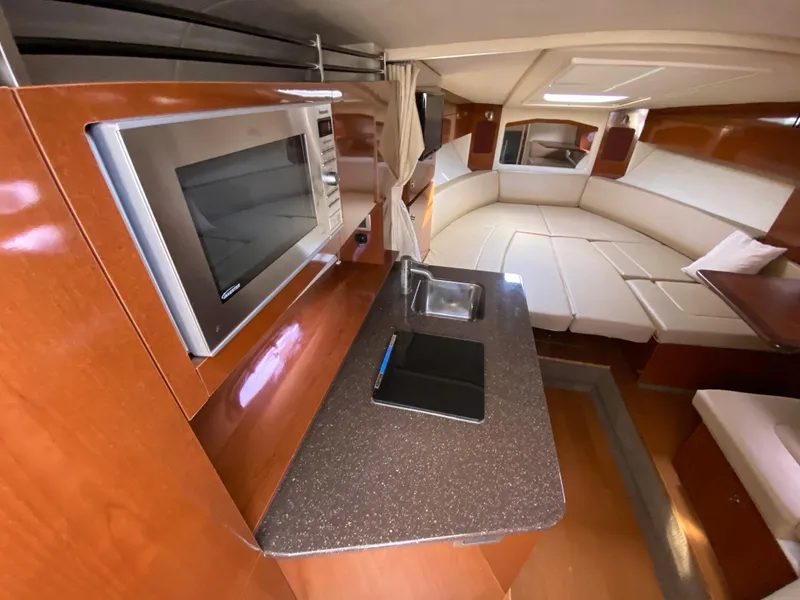 Slide: The Image of 2013 Sea Ray 310 Sundancer interior with kitchenette and seating area. - 12