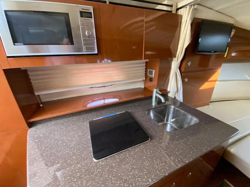 Slide: The Image of 2013 Sea Ray 310 Sundancer galley with microwave, sink, and cooktop. - 13