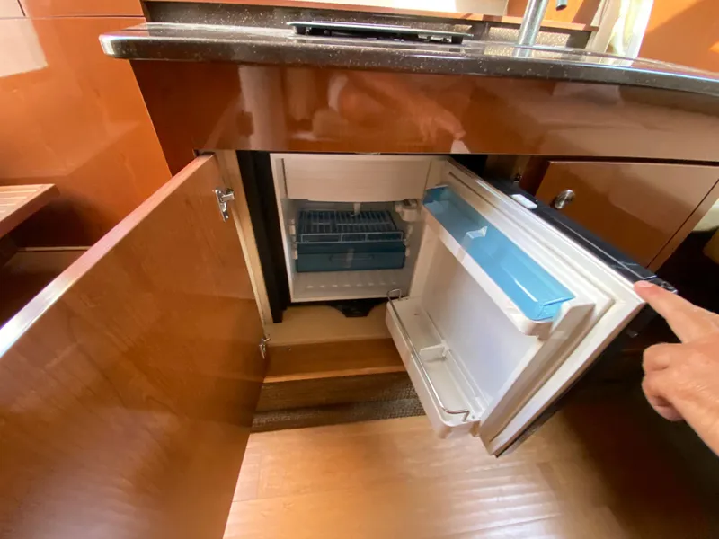 Slide: The Image of 2013 Sea Ray 310 Sundancer interior with open mini fridge under counter. - 15