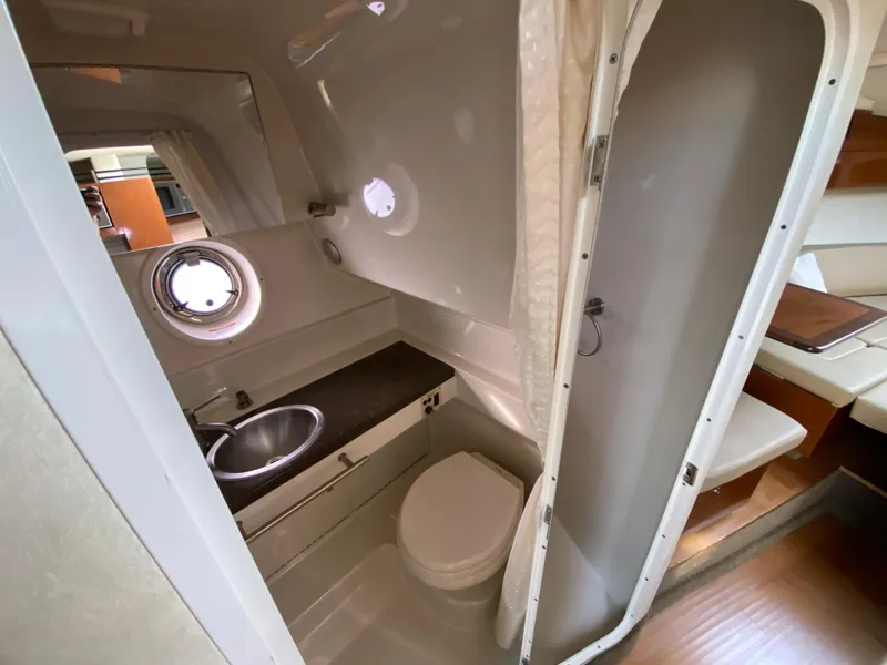 Slide: The Image of 2013 Sea Ray 310 Sundancer bathroom with sink, toilet, and porthole window. - 18