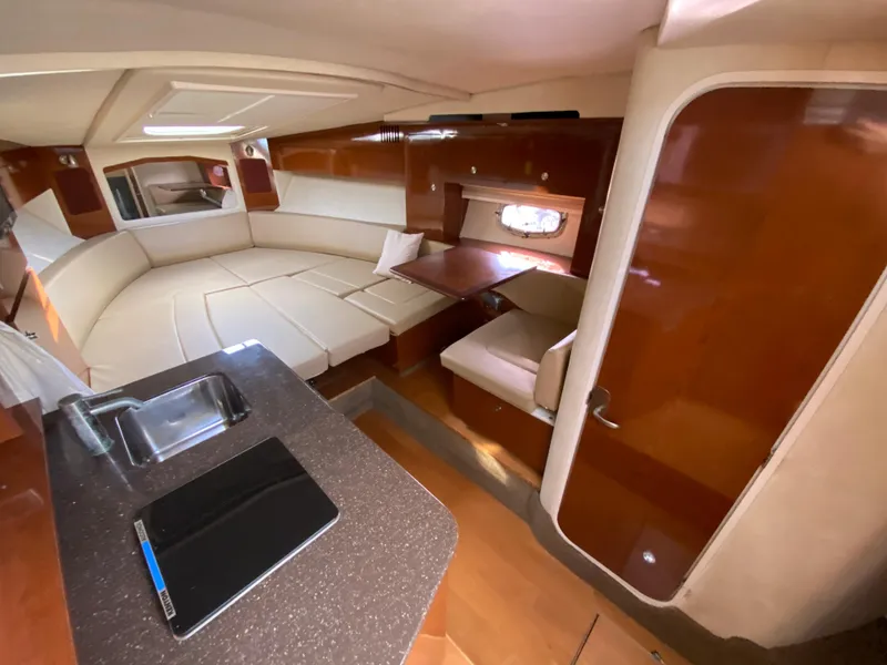 Slide: The Image of 2013 Sea Ray 310 Sundancer cabin interior with seating, table, and kitchenette. - 3