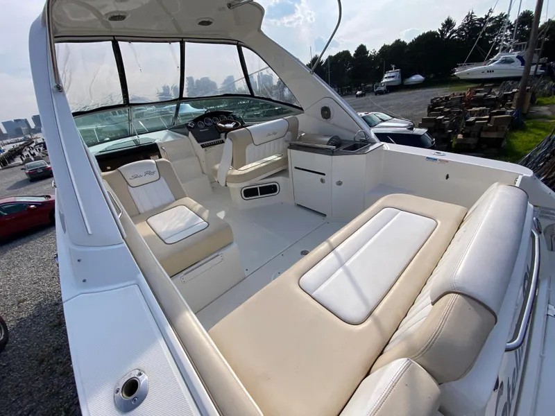 Slide: The Image of 2013 Sea Ray 310 Sundancer boat interior with beige seating and helm, docked outdoors. - 8
