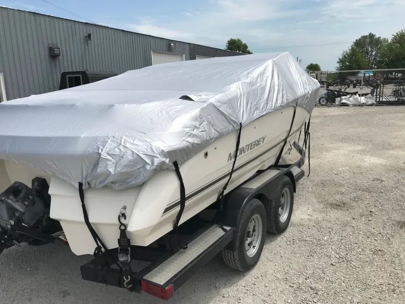 Slide: The Image of 2010 Monterey 214FS boat covered on a trailer in a gravel lot. - 31