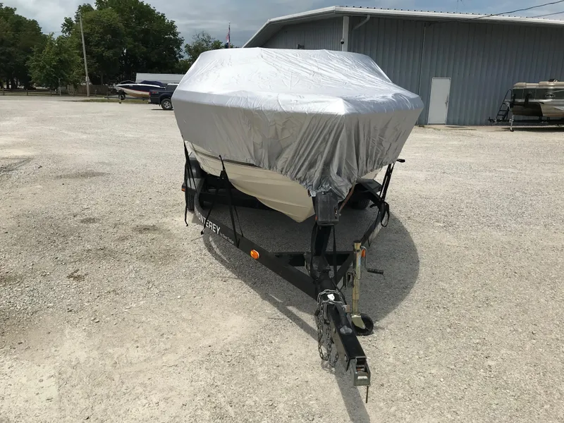 Slide: The Image of 2010 Monterey 214FS boat covered on a trailer in a gravel lot. - 32