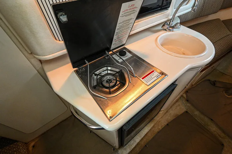 Slide: The Image of Compact kitchen area in a 2001 Sea Ray 260 Sundancer boat with stove and sink. - 25