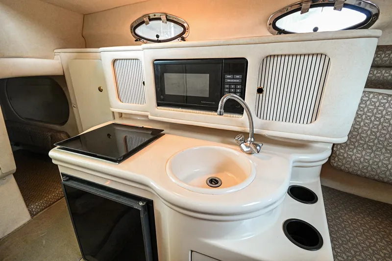 Slide: The Image of 2001 Sea Ray 260 Sundancer kitchen with sink, stove, microwave, and storage cabinets. - 27