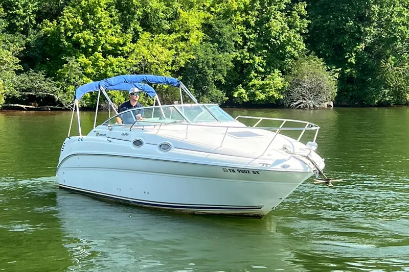 Slide: The Image of 2001 Sea Ray 260 Sundancer boat cruising on a lake with lush green trees in the background. - 3