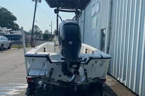 Slide: The Image of 2011 Mako 2201 Inshore boat with outboard motor, parked near a metal building. - 2