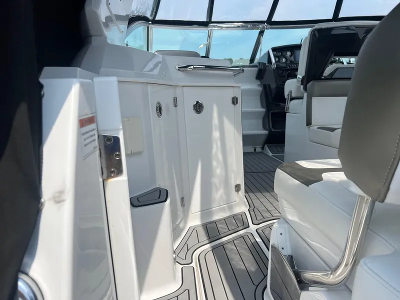 Slide: The Image of Interior of a 2019 Monterey 295 Sport Yacht with white and gray seating. - 12