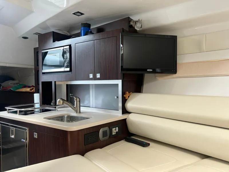 Slide: The Image of 2019 Monterey 295 Sport Yacht interior with kitchenette, TV, and seating area. - 17