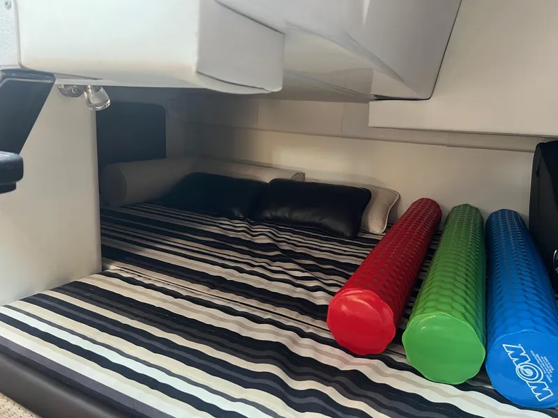 Slide: The Image of 2019 Monterey 295 Sport Yacht interior cabin with striped bedding and colorful foam rollers. - 19