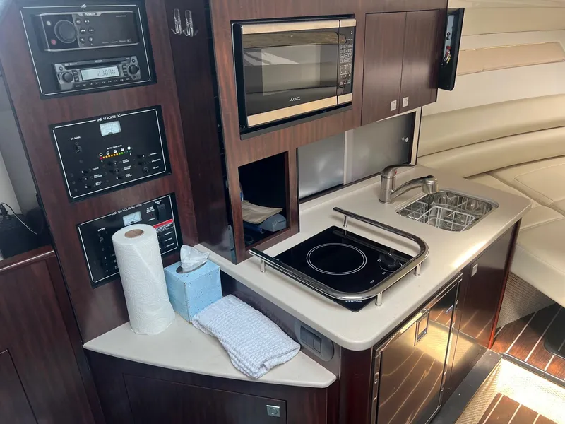 Slide: The Image of 2019 Monterey 295 Sport Yacht kitchen area with microwave, sink, and stove. - 25