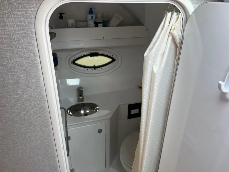 Slide: The Image of 2019 Monterey 295 Sport Yacht bathroom with sink, toilet, and porthole window. - 26