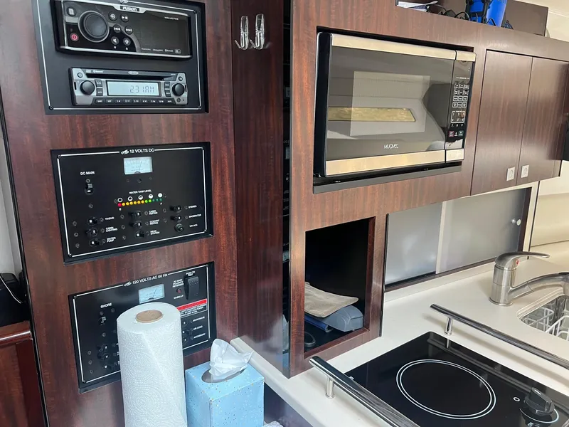 Slide: The Image of 2019 Monterey 295 Sport Yacht kitchen with microwave, stove, and control panels. - 29