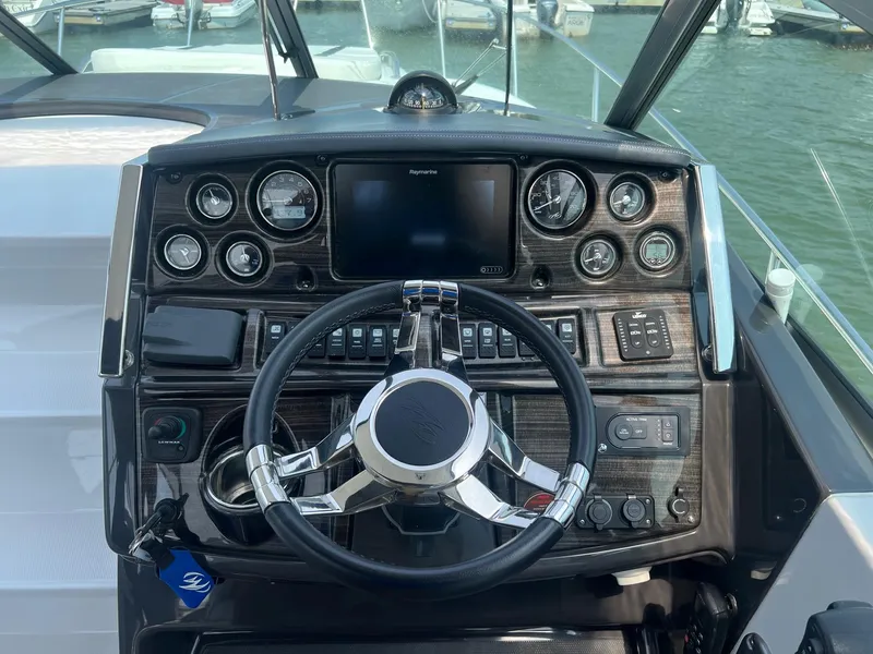 Slide: The Image of 2019 Monterey 295 Sport Yacht dashboard with steering wheel and navigation controls. - 3