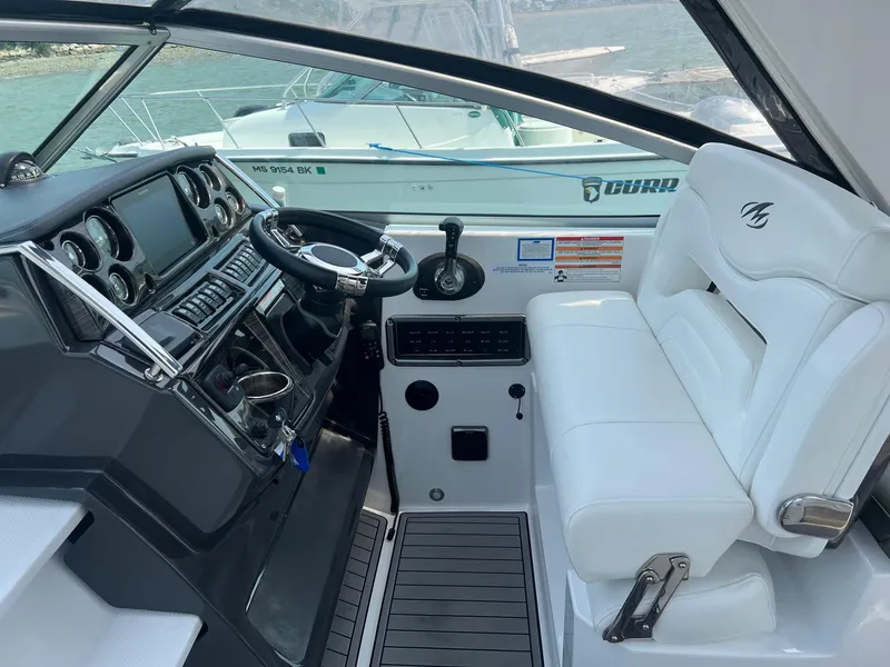 Slide: The Image of 2019 Monterey 295 Sport Yacht cockpit with steering wheel and white seating. - 4