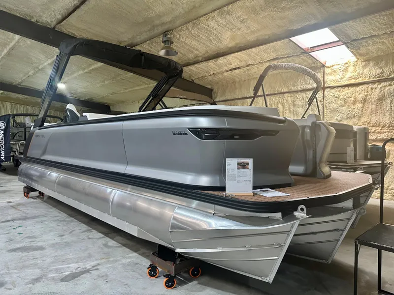 The Image of 2023 Manitou 26 Explore Switchback pontoon boat with trifold bench in indoor storage. - 0