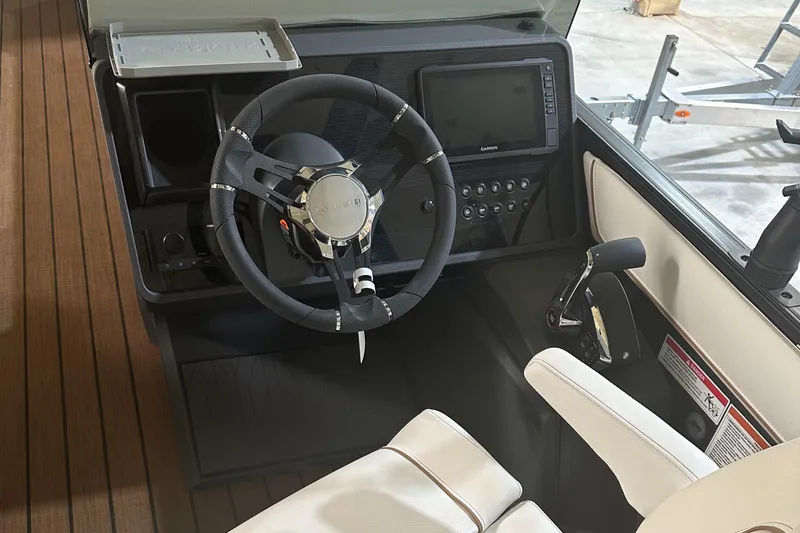 Slide: The Image of 2023 Manitou 26 Explore Switchback boat helm with trifold bench, steering wheel, and control panel. - 8