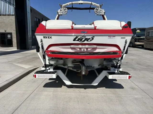 Slide: The Image of 2022 Tigé 23ZX boat rear view, red and white, parked on concrete. - 3