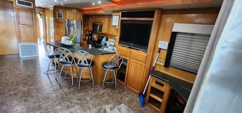 Slide: The Image of 2007 Destination Yachts 16x58 houseboat kitchen with bar stools, TV, and modern appliances. - 16