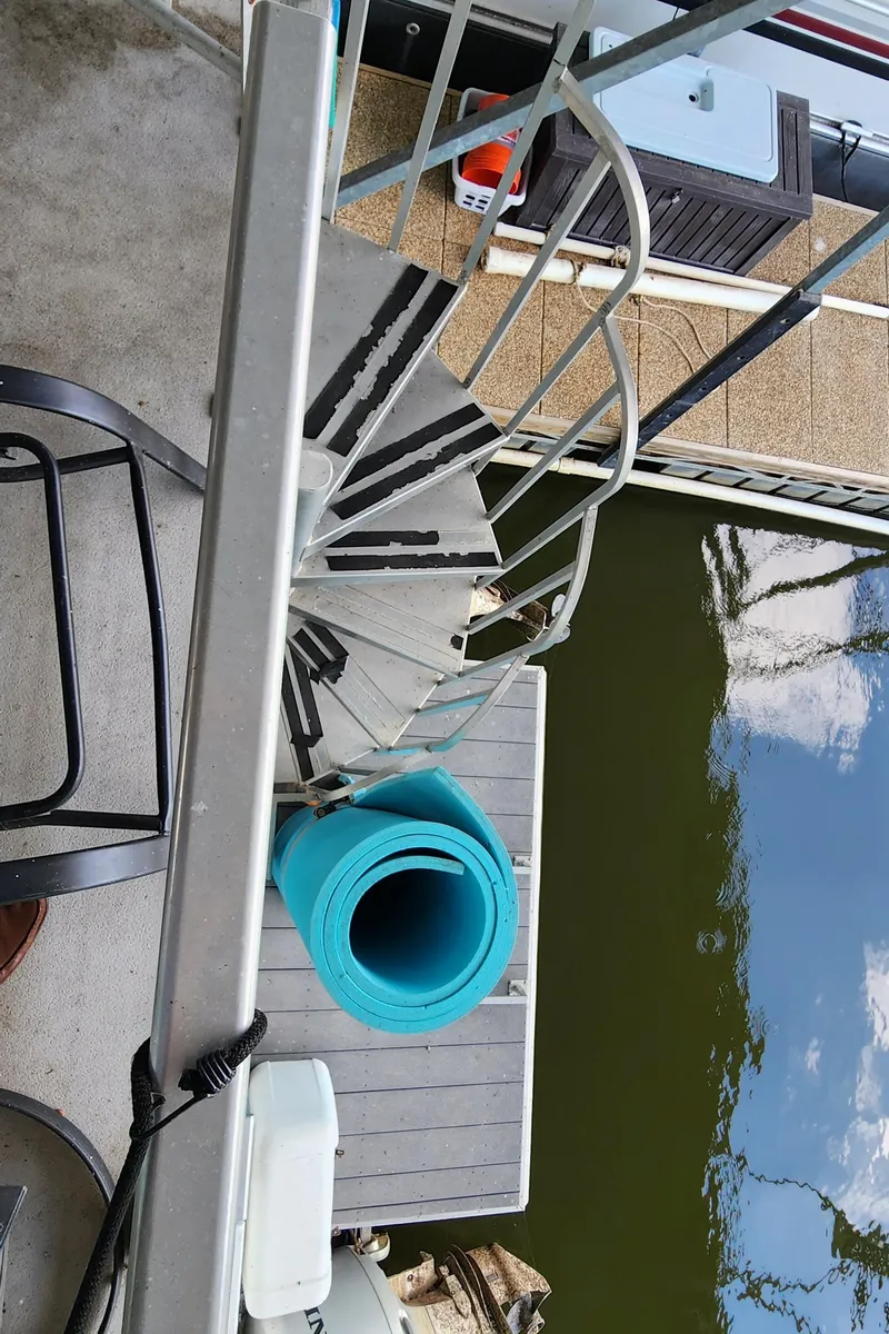 Slide: The Image of View of a 2007 Destination Yachts 16x58 houseboat's spiral staircase and dock. - 18