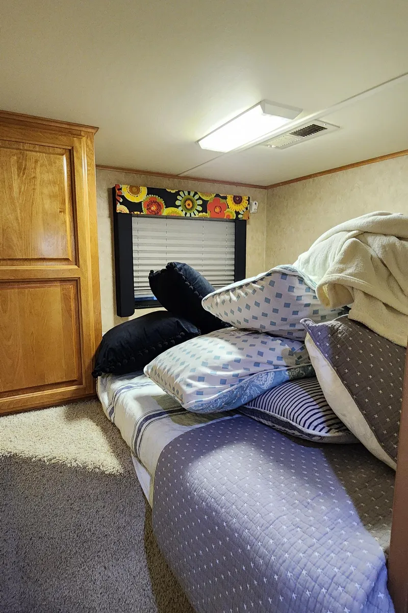 Slide: The Image of Cozy bedroom in a 2007 Destination Yachts 16x58 houseboat with wooden cabinets and colorful window valance. - 29