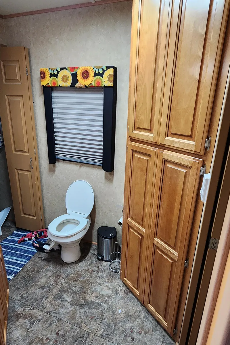 Slide: The Image of Bathroom in a 2007 Destination Yachts 16x58 houseboat with wooden cabinets and sunflower-themed window valance. - 34