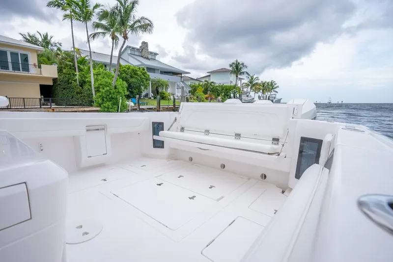 Slide: The Image of 2022 Intrepid 375 Nomad FE boat deck with seating, docked near waterfront homes. - 25