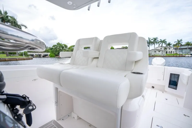 Slide: The Image of 2022 Intrepid 375 Nomad FE boat with white leather seating, docked near waterfront homes. - 27