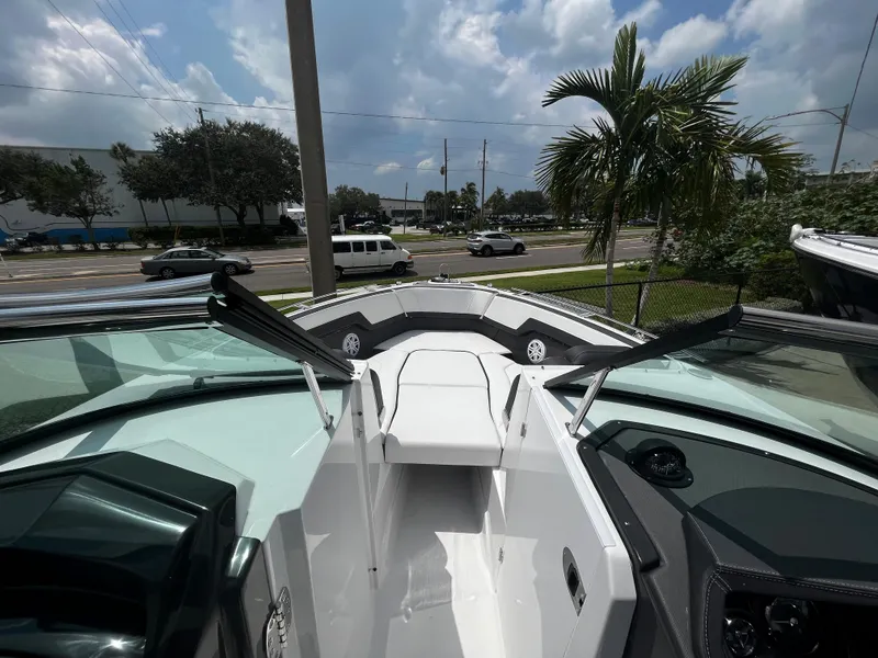 Slide: The Image of 2024 Monterey 275 Super Sport boat interior with seating and windshield, parked near palm trees. - 24