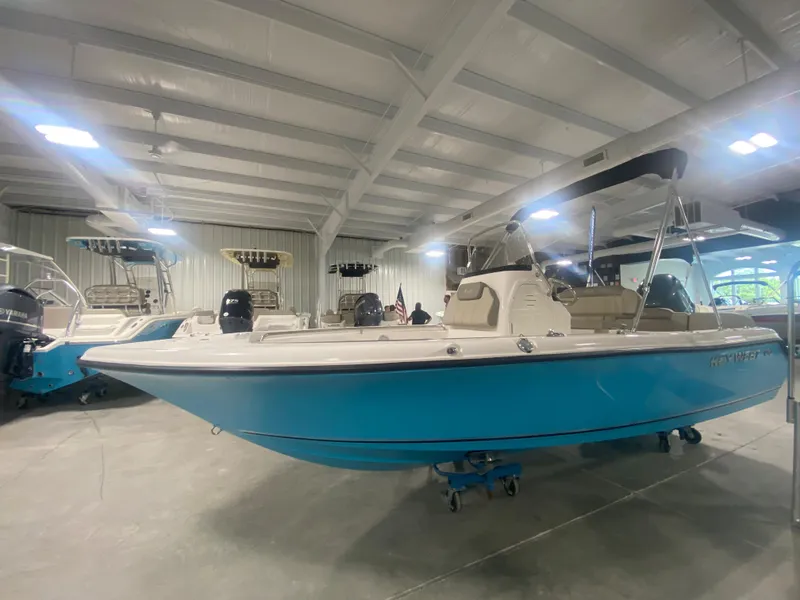 Slide: The Image of 2024 Key West 189 FS boat in showroom, blue hull, beige interior, under bright lights. - 4