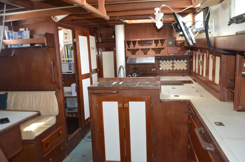 Slide: The Image of Interior of a 1973 Skookum Ketch sailboat with wooden cabinetry and cozy seating. - 10