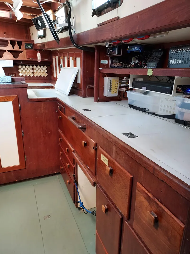Slide: The Image of Interior of a 1973 Skookum Ketch sailboat with wooden cabinetry and organized storage. - 11