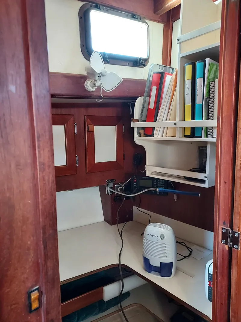 Slide: The Image of Interior of a 1973 Skookum Ketch sailboat with wooden cabinetry and organized workspace. - 13