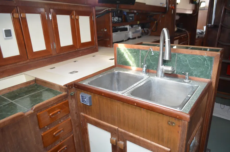 Slide: The Image of 1973 Skookum Ketch kitchen with dual sinks, wooden cabinets, and green countertops. - 19