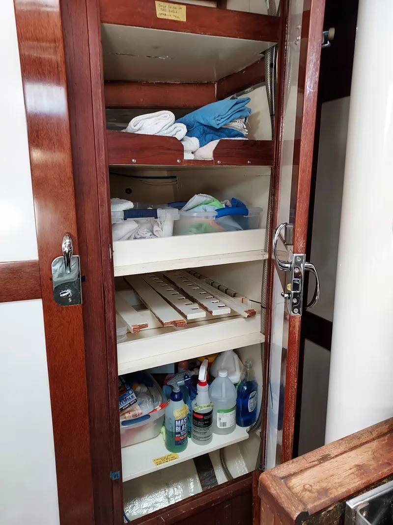 Slide: The Image of Wooden cabinet with shelves storing cleaning supplies and towels on a 1973 Skookum Ketch. - 22