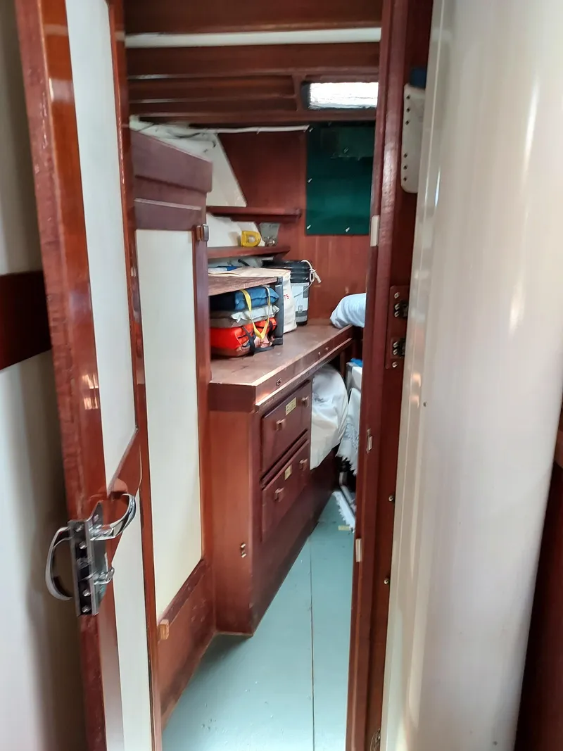 Slide: The Image of Interior view of a 1973 Skookum Ketch sailboat cabin with wooden cabinetry. - 25