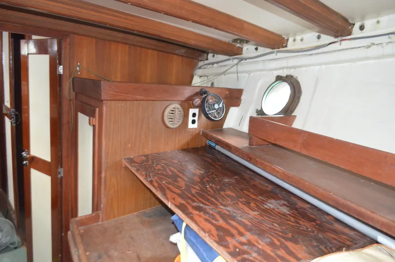 Slide: The Image of Interior of a 1973 Skookum Ketch sailboat with wooden cabinetry and porthole. - 31