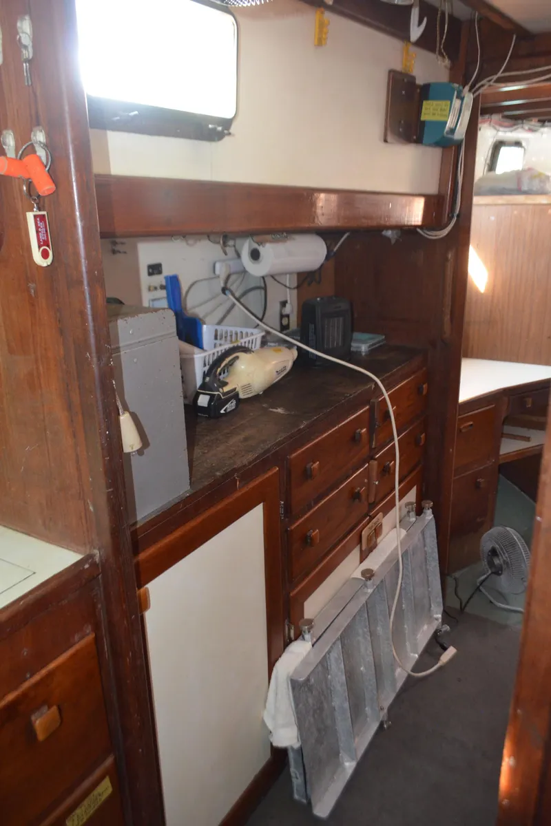 Slide: The Image of Interior of a 1973 Skookum Ketch sailboat with wooden cabinetry and nautical equipment. - 34
