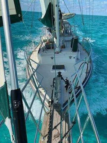 Slide: The Image of 1973 Skookum Ketch sailing on turquoise ocean waters, viewed from the bow. - 4