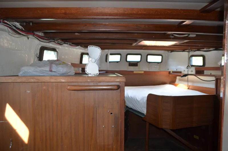 Slide: The Image of Interior of a 1973 Skookum Ketch sailboat with wooden furnishings and a cozy sleeping area. - 40