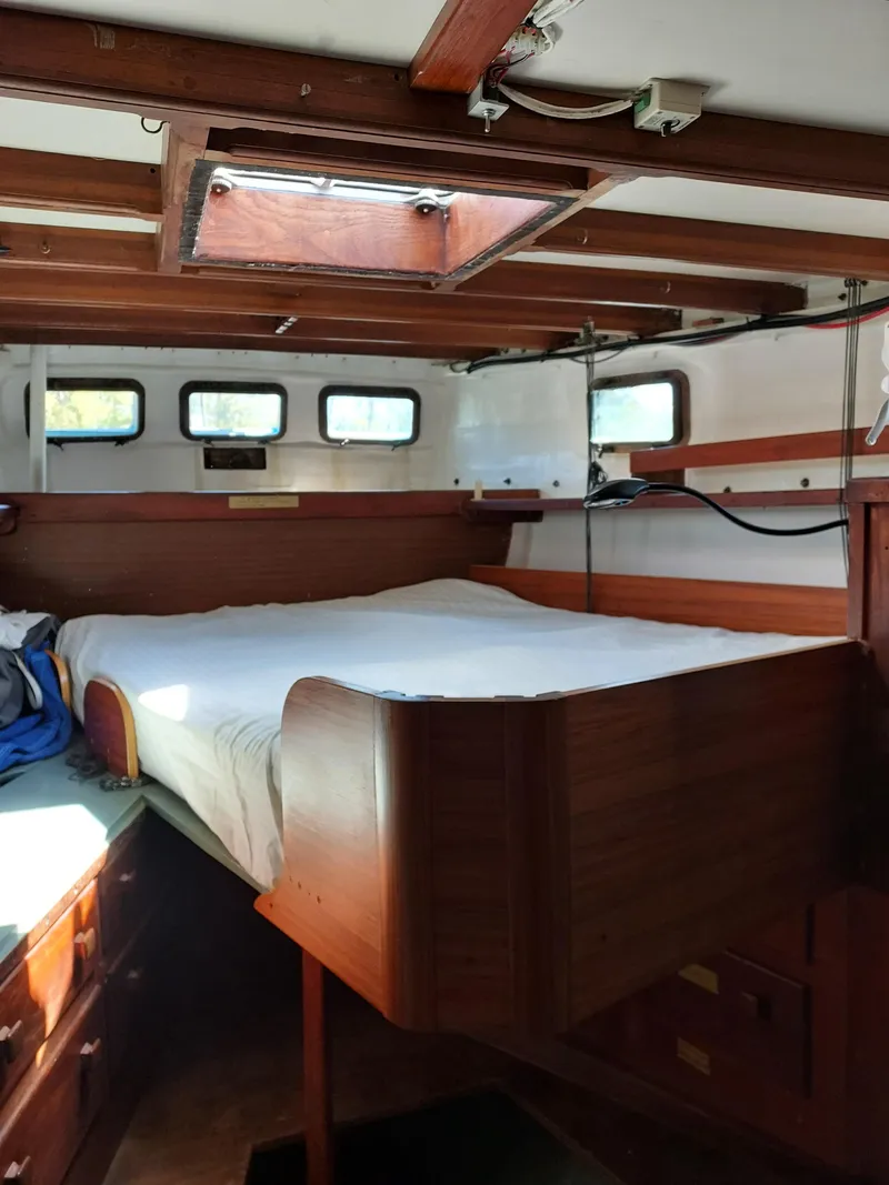 Slide: The Image of Interior of a 1973 Skookum Ketch sailboat with wooden bed and porthole windows. - 41