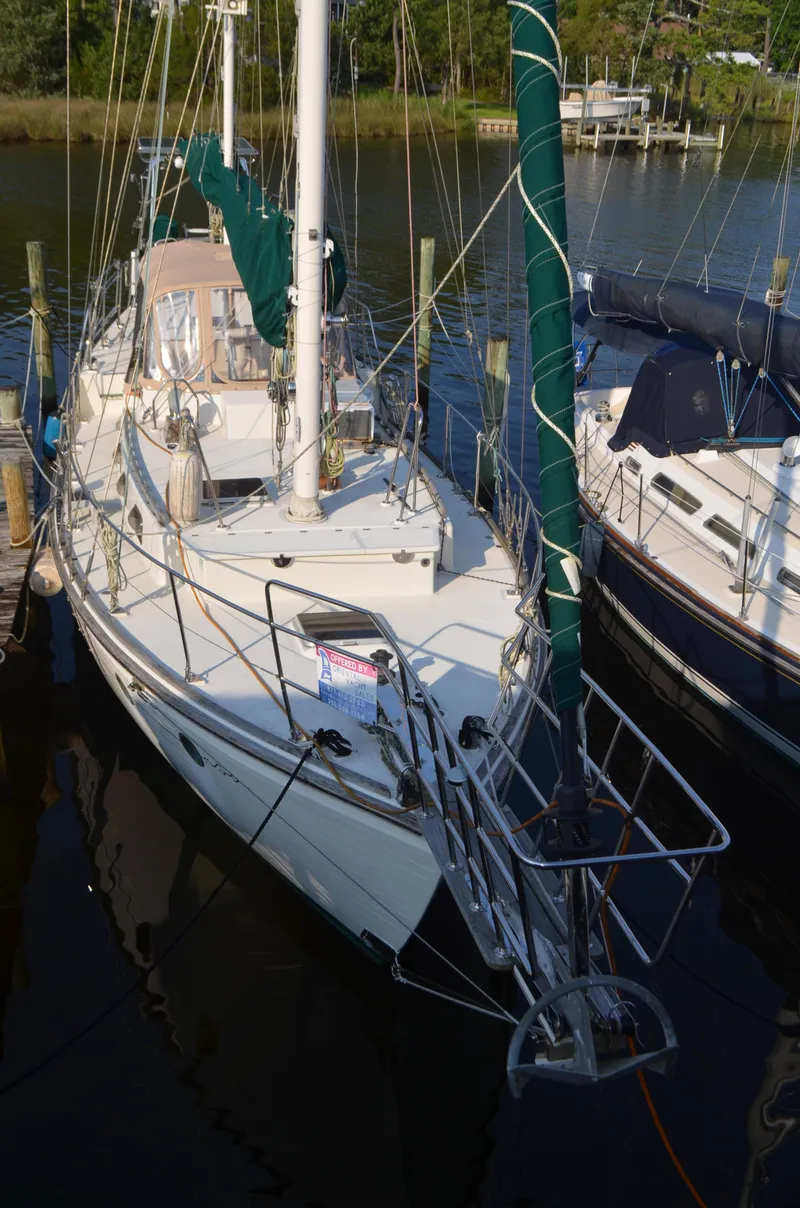 Slide: The Image of 1973 Skookum Ketch sailboat docked in a marina, featuring green sails and a white deck. - 5