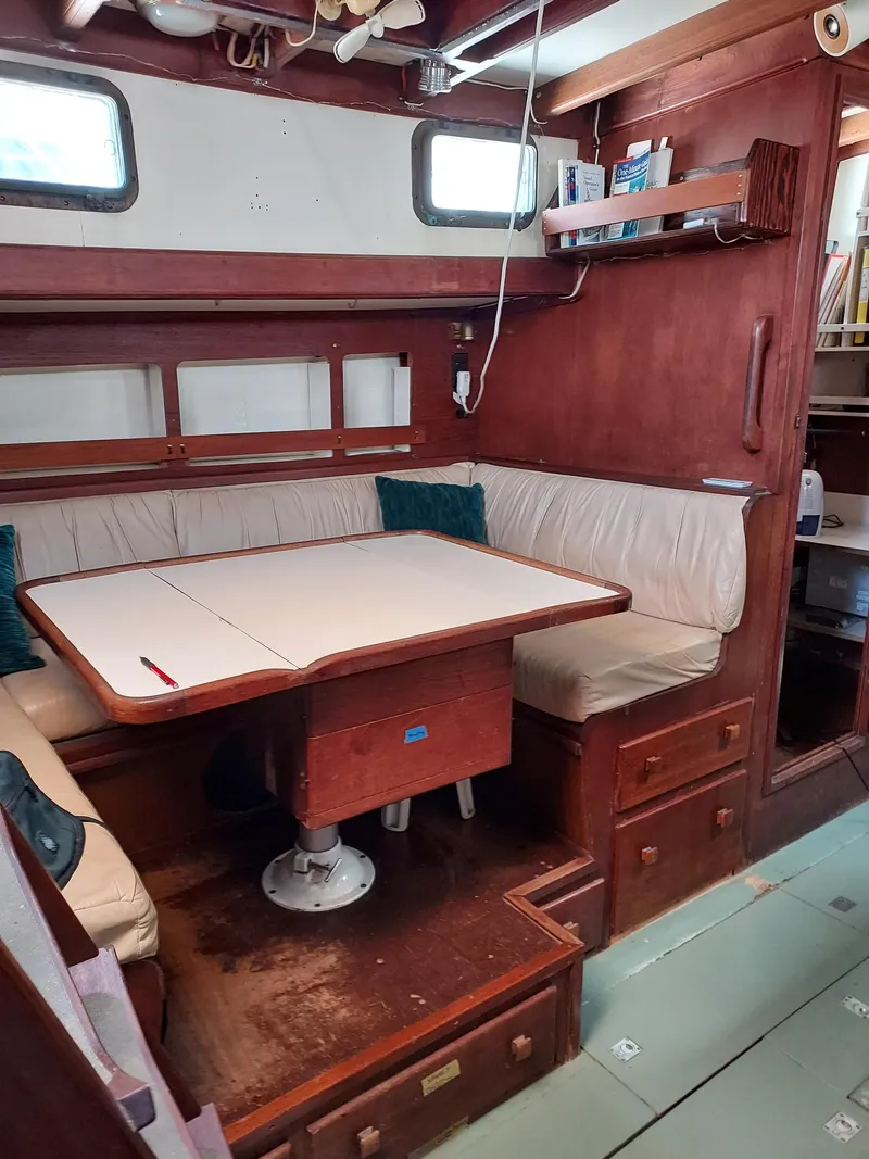 Slide: The Image of 1973 Skookum Ketch interior with wooden dining area and cushioned seating. - 9