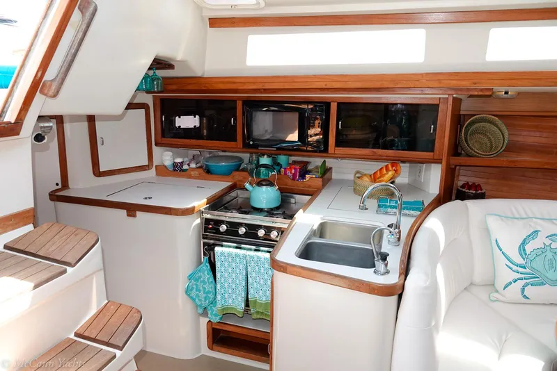 Slide: The Image of Interior of a 1991 Catalina 42 sailboat kitchen with stove, sink, and wooden cabinetry. - 13