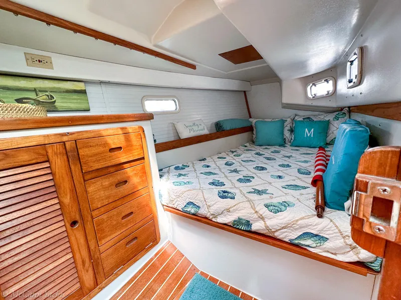 Slide: The Image of Cozy cabin interior of a 1991 Catalina 42 sailboat with nautical-themed bedding and wooden cabinetry. - 19